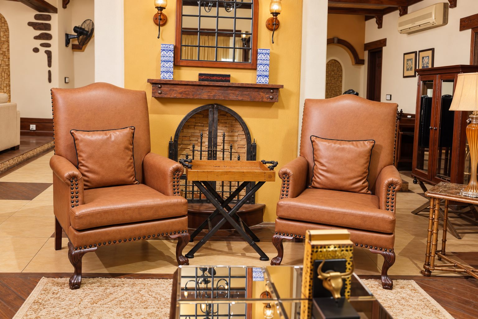 Pair of tan leather wingback chairs by the fireplace